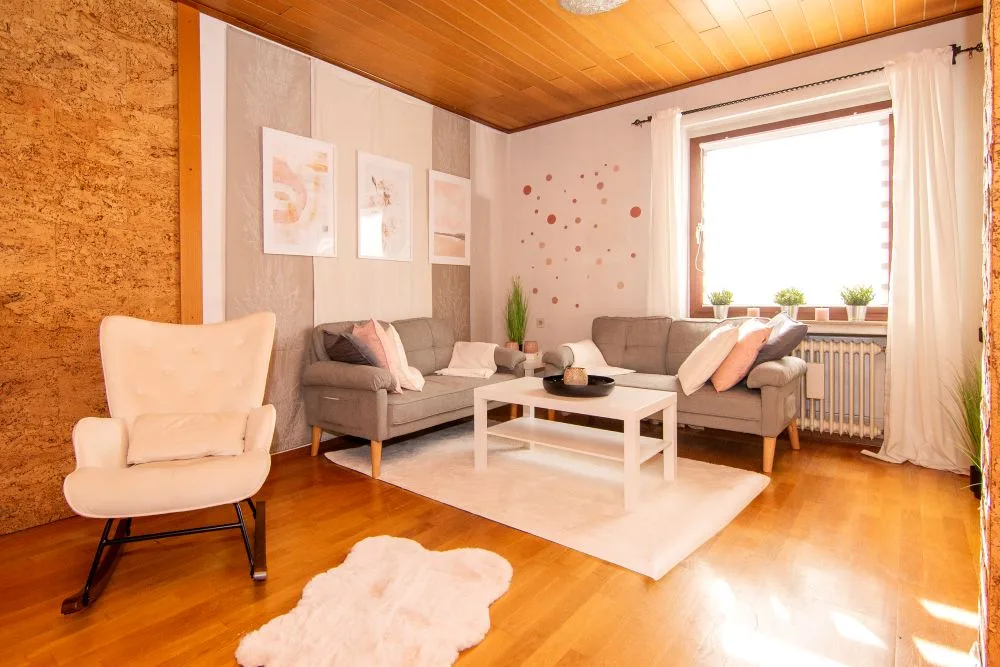 Wohnzimmer nach dem Home Staging: helle Sofas, Sessel, Couchtisch und Bilder in ruhigen Farben
